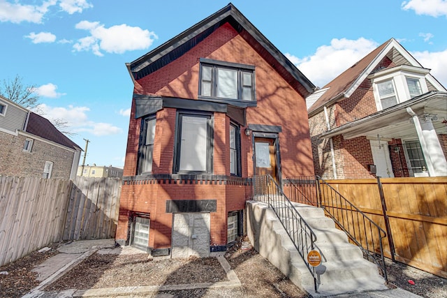 view of front facade featuring brick siding and fence private yard