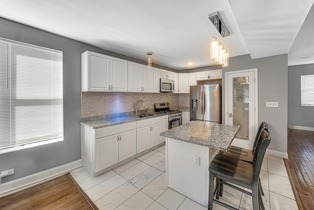 kitchen featuring a sink, marble finish floor, appliances with stainless steel finishes, and white cabinets