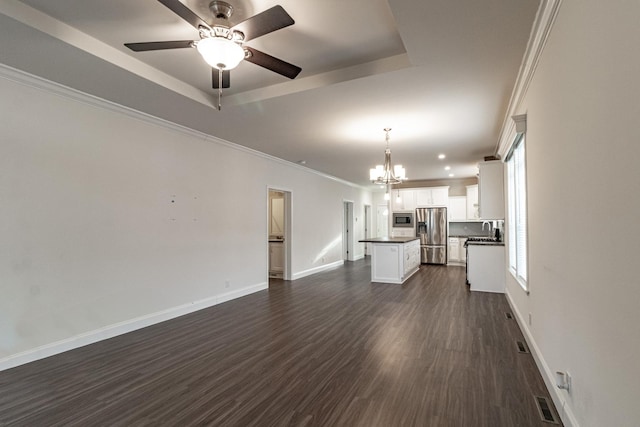 unfurnished living room featuring baseboards, a tray ceiling, dark wood-style flooring, a sink, and crown molding