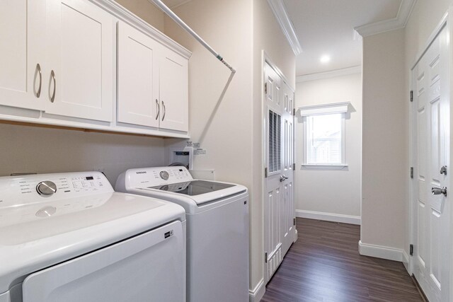 clothes washing area featuring ornamental molding, dark wood-style floors, washing machine and dryer, cabinet space, and baseboards