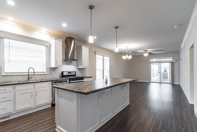 kitchen featuring a kitchen island, a sink, appliances with stainless steel finishes, wall chimney range hood, and backsplash