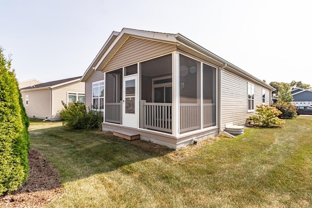 back of property with a lawn and a sunroom