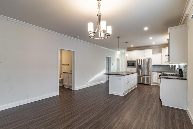 kitchen with a kitchen island, dark wood-style flooring, stainless steel appliances, dark countertops, and a chandelier