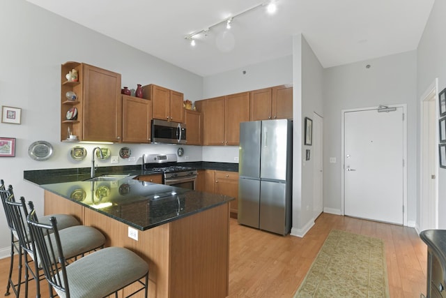 kitchen featuring a sink, appliances with stainless steel finishes, a peninsula, brown cabinetry, and open shelves