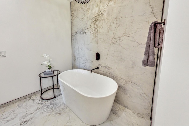 bathroom featuring a freestanding tub and marble finish floor