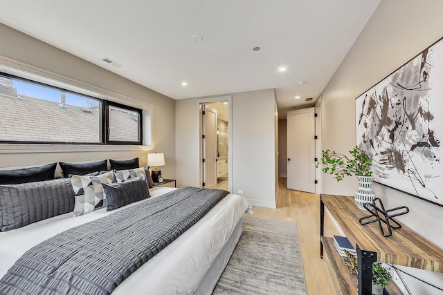 bedroom featuring light wood finished floors, visible vents, baseboards, recessed lighting, and ensuite bathroom