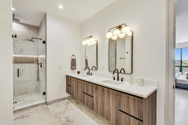 ensuite bathroom with a marble finish shower, marble finish floor, and a sink