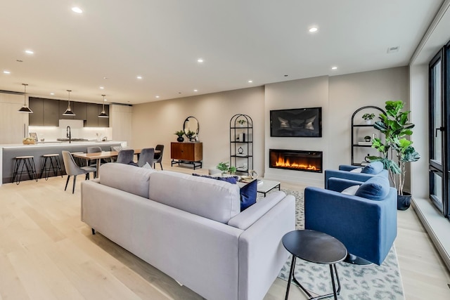 living area with recessed lighting, light wood-type flooring, visible vents, and a glass covered fireplace