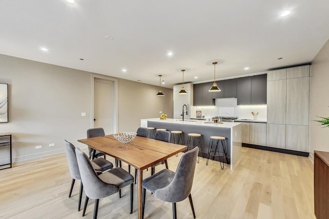 dining room with light wood finished floors, recessed lighting, and baseboards