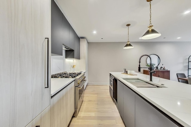 kitchen with high end appliances, light wood-style flooring, a sink, light countertops, and modern cabinets