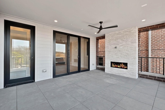 view of patio with a ceiling fan and a fireplace