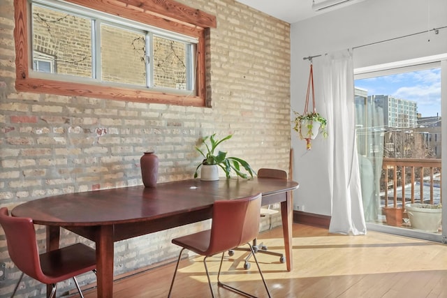 dining space with brick wall and wood finished floors