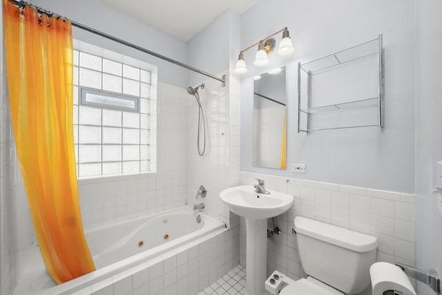 full bath featuring toilet, tile walls, wainscoting, and a combined bath / shower with jetted tub