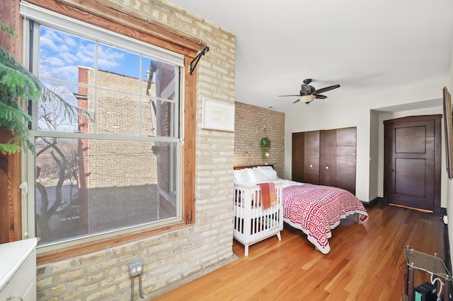 bedroom with wood finished floors, a closet, and brick wall