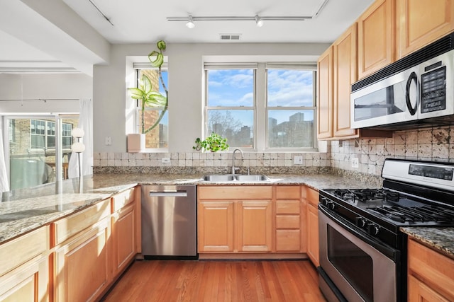 kitchen with visible vents, a sink, decorative backsplash, appliances with stainless steel finishes, and light wood-type flooring