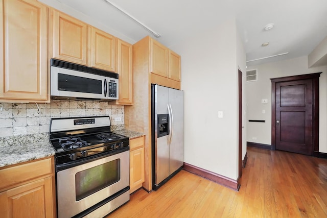 kitchen featuring visible vents, light brown cabinetry, light wood-type flooring, decorative backsplash, and stainless steel appliances