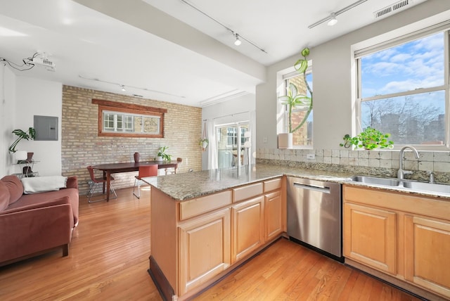 kitchen featuring visible vents, a sink, light stone counters, light wood-style floors, and dishwasher