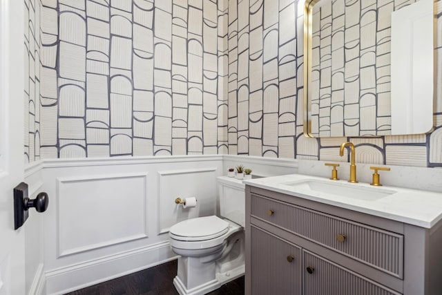 bathroom featuring toilet, vanity, and a decorative wall