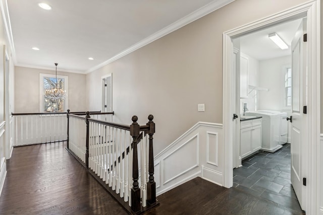 hall featuring a wainscoted wall, an upstairs landing, a notable chandelier, crown molding, and dark wood-style flooring