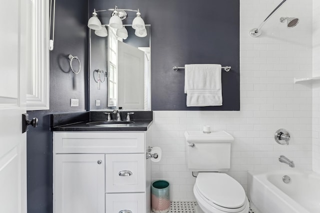 bathroom with washtub / shower combination, toilet, vanity, wainscoting, and tile walls