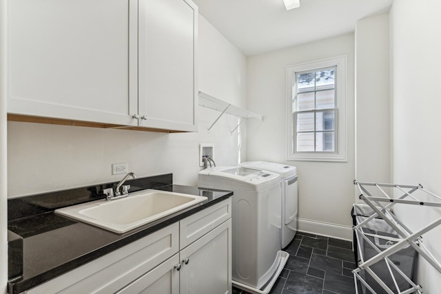 laundry room with stone finish floor, a sink, washer and dryer, cabinet space, and baseboards