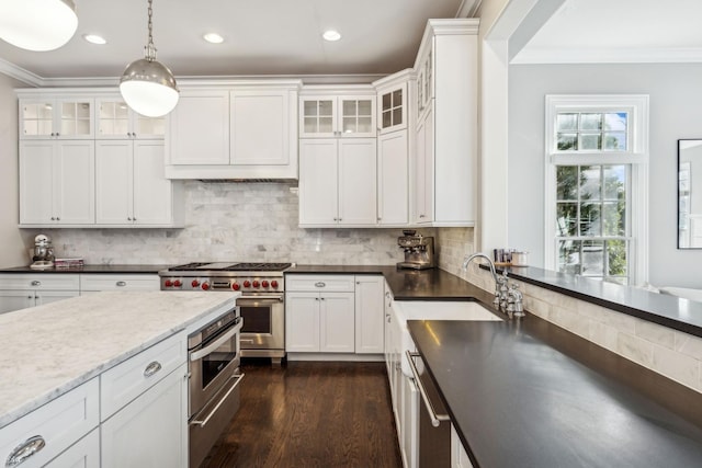 kitchen featuring ornamental molding, decorative backsplash, appliances with stainless steel finishes, white cabinets, and a sink