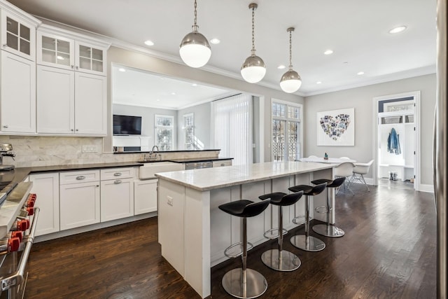 kitchen with dark wood-style flooring, a healthy amount of sunlight, a peninsula, and a sink