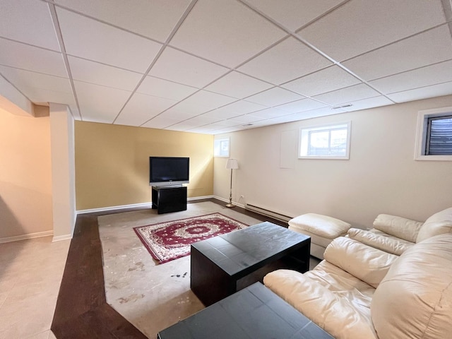 living area with a drop ceiling, a baseboard heating unit, and baseboards