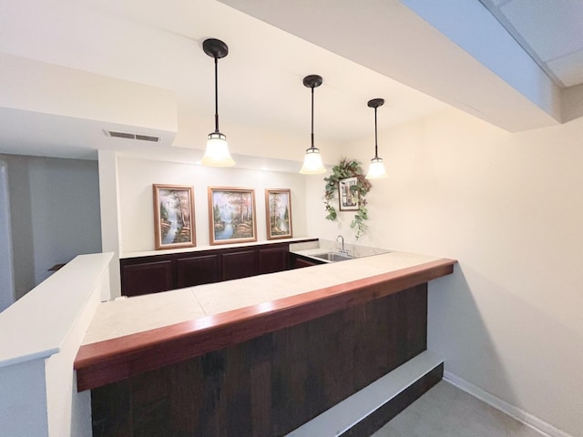 bar with a sink, visible vents, baseboards, and pendant lighting