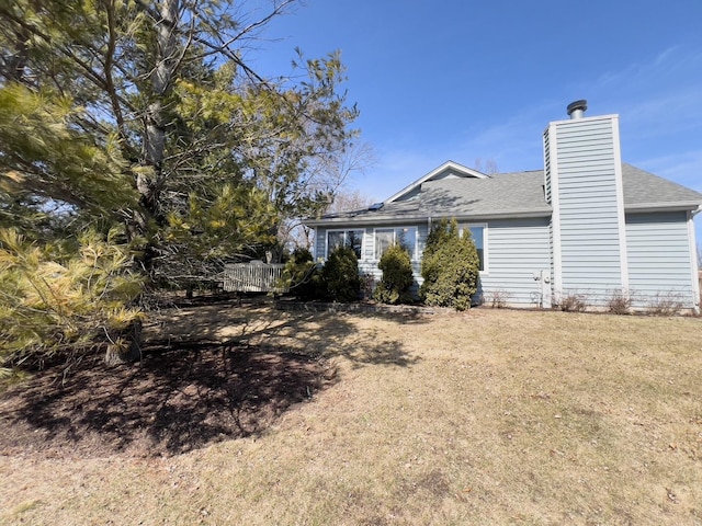 back of property featuring a lawn, fence, roof with shingles, and a chimney