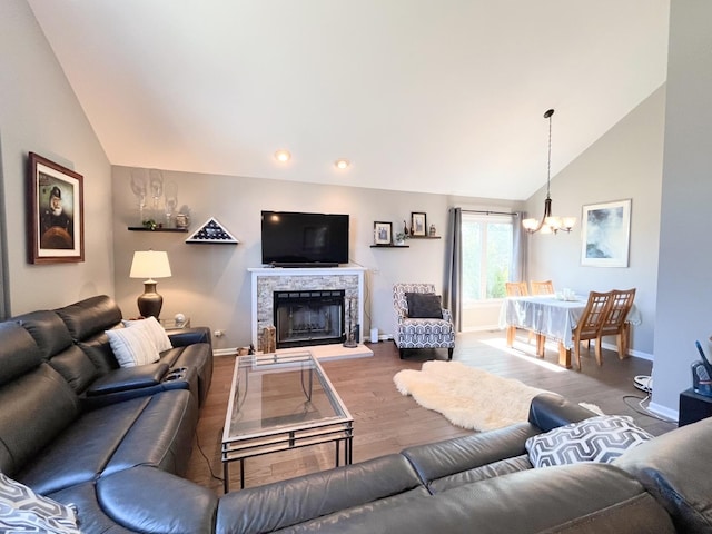 living room featuring a fireplace, vaulted ceiling, wood finished floors, and a chandelier