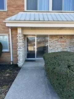 entrance to property featuring metal roof, a balcony, and a standing seam roof