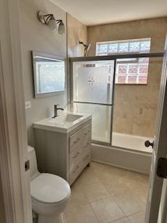 full bathroom featuring vanity, tile patterned floors, toilet, and enclosed tub / shower combo