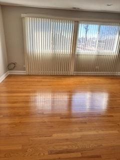 spare room with baseboards and wood finished floors