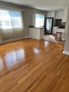 unfurnished living room with baseboards, plenty of natural light, and wood finished floors