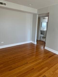 spare room with visible vents, wood finished floors, and baseboards