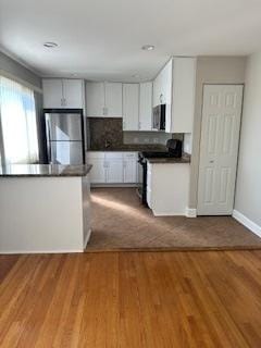 kitchen with dark countertops, refrigerator, stainless steel microwave, and electric range oven