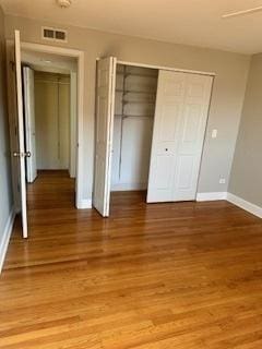 unfurnished bedroom featuring visible vents, baseboards, a closet, and light wood finished floors