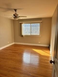 spare room featuring ceiling fan, baseboards, and wood finished floors