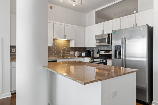 kitchen with stone counters, appliances with stainless steel finishes, decorative backsplash, and a sink