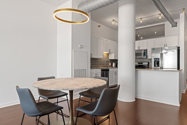 dining area with visible vents, dark wood-style floors, rail lighting, baseboards, and a towering ceiling