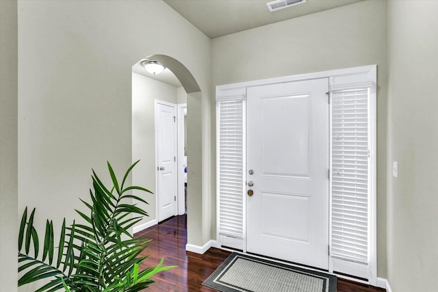 entryway with baseboards, arched walkways, visible vents, and wood finished floors