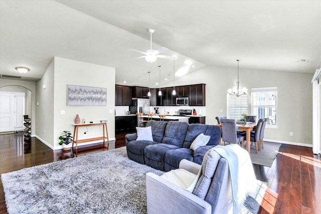 living area featuring visible vents, baseboards, lofted ceiling, ceiling fan with notable chandelier, and dark wood-style floors