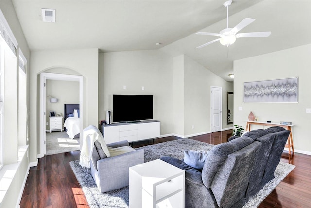 living area featuring visible vents, dark wood-type flooring, lofted ceiling, arched walkways, and baseboards