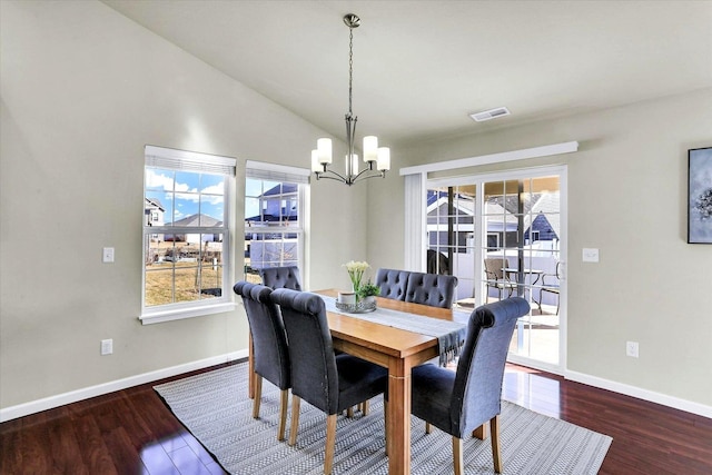 dining space featuring visible vents, baseboards, vaulted ceiling, wood finished floors, and a notable chandelier