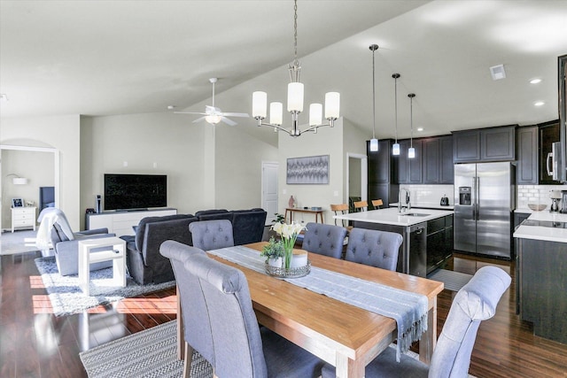 dining room with dark wood-type flooring, ceiling fan with notable chandelier, arched walkways, and vaulted ceiling