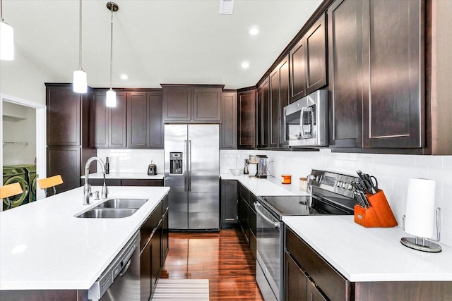 kitchen with dark wood finished floors, a sink, stainless steel appliances, dark brown cabinetry, and light countertops