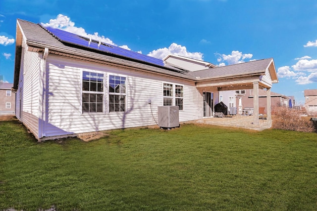 back of property featuring a yard, roof mounted solar panels, central AC, and a patio area