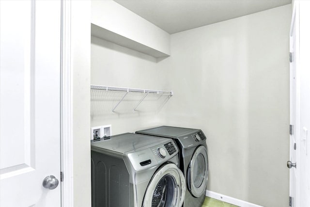 washroom with baseboards, laundry area, and washing machine and clothes dryer