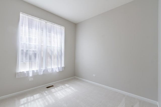 empty room featuring light colored carpet, visible vents, and baseboards